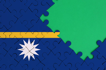 Nauru flag  is depicted on a completed jigsaw puzzle with free green copy space on the right side