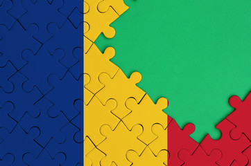 Romania flag  is depicted on a completed jigsaw puzzle with free green copy space on the right side
