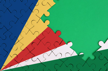 Seychelles flag  is depicted on a completed jigsaw puzzle with free green copy space on the right...
