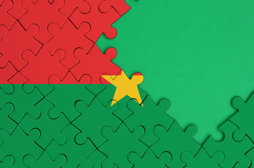 Burkina Faso flag  is depicted on a completed jigsaw puzzle with free green copy space on the right...