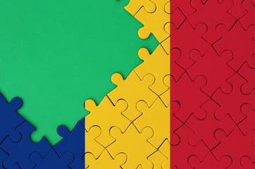 Romania flag  is depicted on a completed jigsaw puzzle with free green copy space on the left side