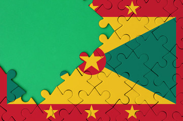 Grenada flag  is depicted on a completed jigsaw puzzle with free green copy space on the left side