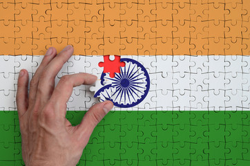 India flag  is depicted on a puzzle, which the man's hand completes to fold