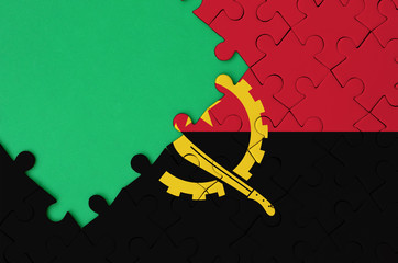 Angola flag  is depicted on a completed jigsaw puzzle with free green copy space on the left side
