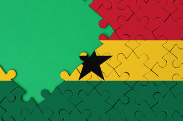 Ghana flag  is depicted on a completed jigsaw puzzle with free green copy space on the left side
