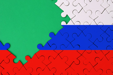Slovenia flag  is depicted on a completed jigsaw puzzle with free green copy space on the left side