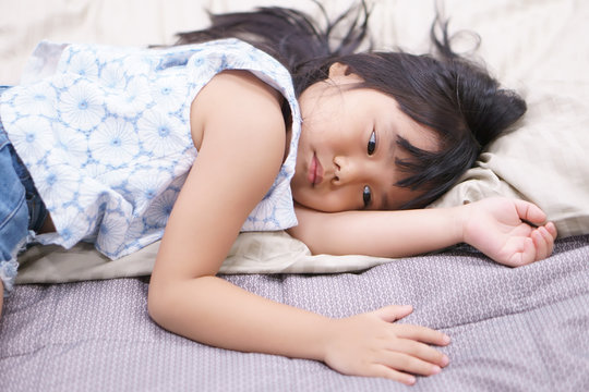 Asian Children Cute Or Kid Fashion Girl Wake Up In Morning Or Sleeping And Sad With Unhappy Or Miss Something On White Bed Lonely With Brown Pillow And Bedtime In Bedroom At Home Or Hotel