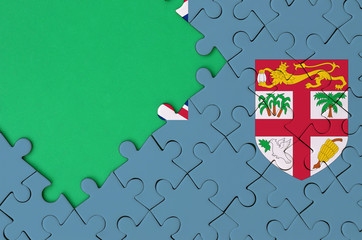 Fiji flag  is depicted on a completed jigsaw puzzle with free green copy space on the left side
