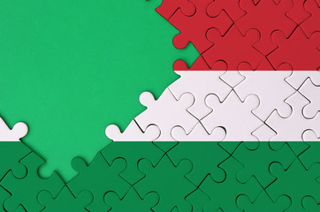 Hungary flag  is depicted on a completed jigsaw puzzle with free green copy space on the left side