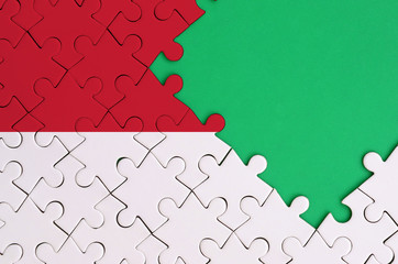 Indonesia flag  is depicted on a completed jigsaw puzzle with free green copy space on the right...