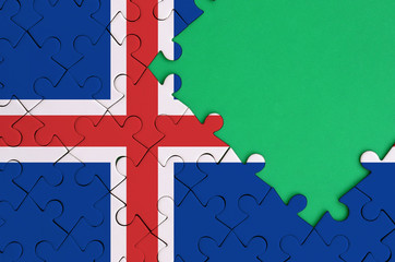 Iceland flag  is depicted on a completed jigsaw puzzle with free green copy space on the right side