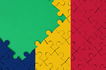 Chad flag  is depicted on a completed jigsaw puzzle with free green copy space on the left side