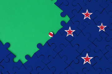New Zealand flag  is depicted on a completed jigsaw puzzle with free green copy space on the left...