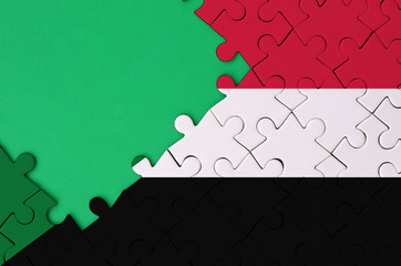 Sudan flag  is depicted on a completed jigsaw puzzle with free green copy space on the left side