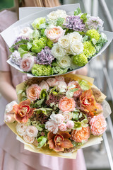 two beautiful luxury bouquet of mixed flowers in woman hand. the work of the florist at a flower shop. A small family business. photo outside