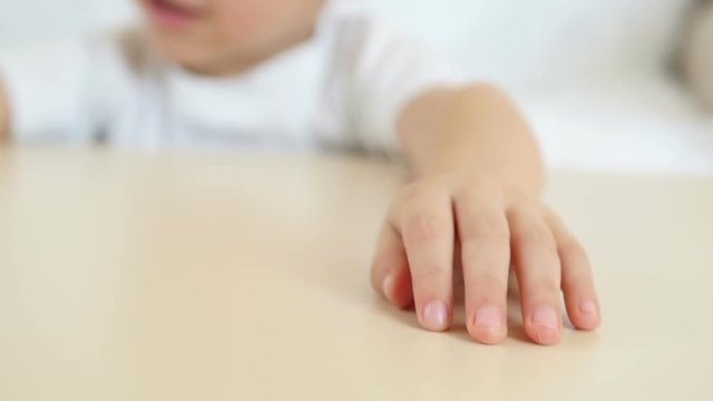 A kid shows his hand close-up on a table