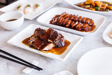 Cantonese roasted duck meat with duck roasted sauce with BBQ Pork in background.