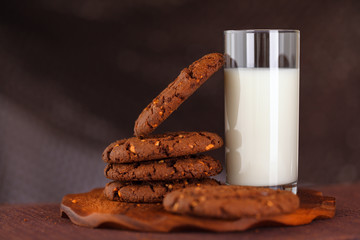 chocolate and nut cookies and a glass of milk on an wooden board