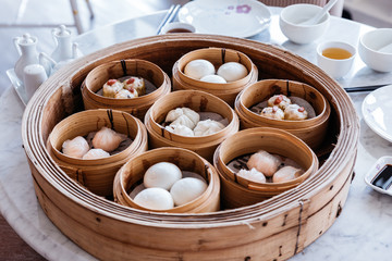 Dim sum set: Barbecued pork bun, Shrimp dumpling, Sweet cream buns, Shrimp shumai topping with goji berry served in steamer baskets.