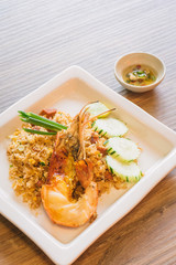 The popular Thai street food is Giant freshwater prawn fried rice on wooden table.