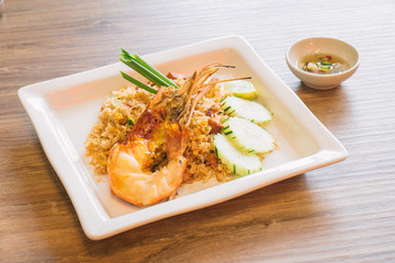 The popular Thai street food is Giant freshwater prawn fried rice on wooden table.