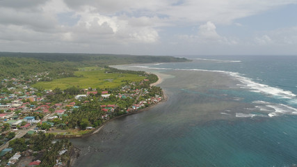 Fototapeta na wymiar Aerial view of seashore with coastal town, beach, lagoons and coral reefs. Bulusan, Philippines, Luzon. Ocean coastline with turquoise water. Tropical landscape in Asia.