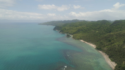 Fototapeta premium Aerial view coastline with beach and mountains covered with tropical forest in province Caramoan, Philippines. Landscape with sea, mountains and beach.