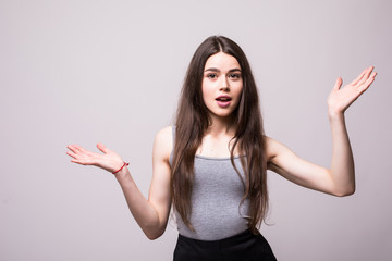 Portrait of young woman shrugging shoulders over gray background