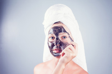 Close up shot of a beauty young woman using a black face mask