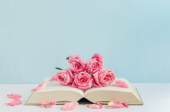 Fototapeta Vintage pink rose flowers with book on white and blue wooden background
