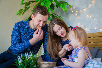 Happy young parents and their baby daughter playing togerher at home. Family, childhood and leisure concept