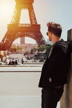 Young man looks to the tour eiffel. The bearded man is dressed silk in his sunglasses