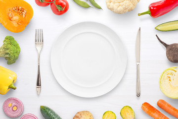 Empty plate fork and knife surrounded with vegetables. Flat lay, close up.