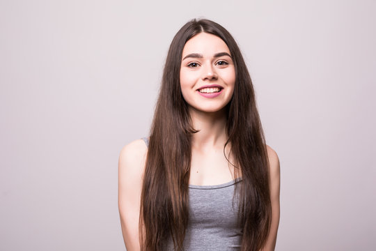 Beautiful young sexy woman in a light gray dress posing against a on gray
