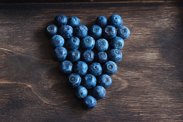Ripe blueberry heart wooden brown background selective focus.