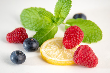 Berries with mint and lemon on white background