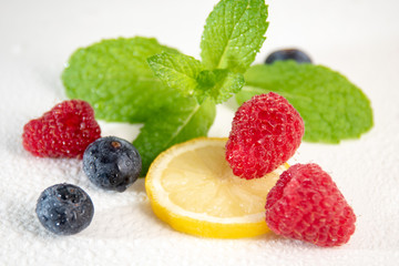 Berries with mint and lemon on white background
