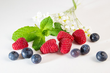 Berries with mint and lemon on white background
