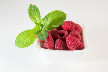 Raspberries with mint on white background