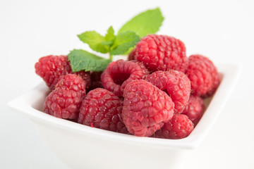 Raspberries with mint on white background