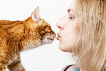 Closeup portrait of young woman kissing ginger cat on white background