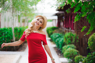 Beautiful girl in elegant dress and hat and charming smile posing for the photographer in the park