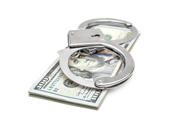 Stack of dollar bills and handcuffs on white.