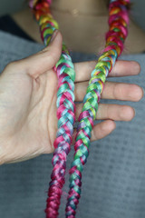 thick colored braids with kanekalon, pink hair, close-up of braid, master holds in hand, ready hairdo in close-up detail