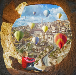 Naklejka premium Woman watching like colorful hot air balloons flying over the valley at Cappadocia, Turkey. Volcanic mountains in Goreme national park.