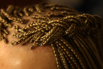 Fototapeta premium texture of thin African braids classic hairstyle African American, European hair, blond, girls with white skin, close-up hairstyle, pigtails in details