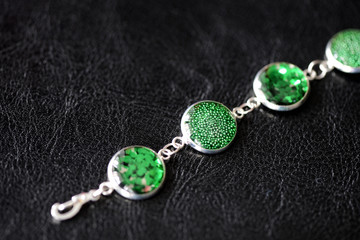 Fototapeta na wymiar Green resin bracelet on a dark background close up