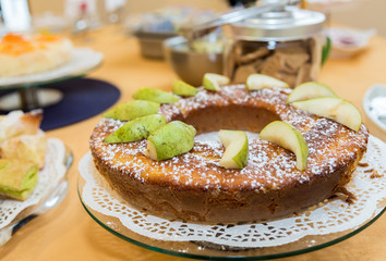 Sweet breakfast. Circular sponge cake with pear slices and icing sugar