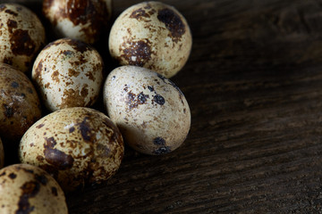 Obraz premium Spotted quail eggs arranged on the background of old wooden boards, with copy-space, selective focus.