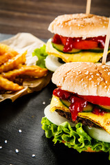 Tasty cheeseburgers with french fries served on fashionable black desk